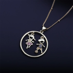 Macro detail of gold necklace pendant featuring boy and girl with colorful gemstones