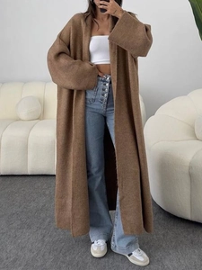 Vue complète d'un long gilet en maille marron porté avec un jean et des baskets blanches