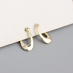 Detailed view of polished gold geometric U-shaped silver hoop earrings on a white card