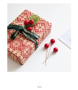 Detail of red snowflake gift box with Merry Christmas ribbon and berry picks