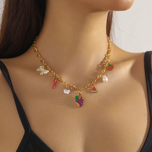Goldene Edelstahl-Halskette mit bunten Fruchtanhängern und Perlen an einem weiblichen Model