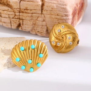 Close-up of vintage gold metal ear clips with blue beads and crystals on a stone