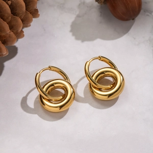 Minimalist double hoop earrings in 18K gold finish on a white marble surface background