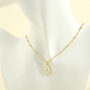 Detailed view of gold envelope pendant with heart detail on a white mannequin neck