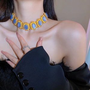 Macro view of vintage golden necklace with oval blue gemstones worn by a model