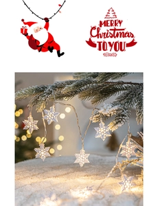 Detail of warm white LED snowflake string lights on frosted pine branches for Christmas decor