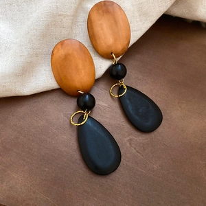 Close-up of bohemian wood drop earrings featuring geometric brown and black beads