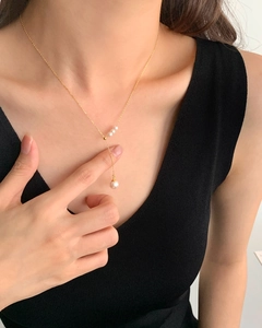 Detail of s925 silver fringe necklace with three white pearls on a gold chain
