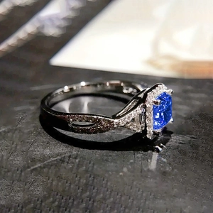 Vue latérale macro d'une bague avec pierre bleue carrée et anneau torsadé serti de diamants