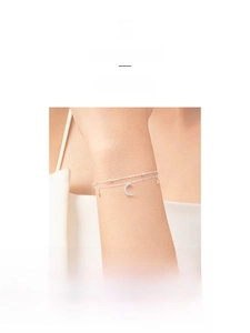 Detail view of silver double-layered star and moon bracelet on a woman wrist