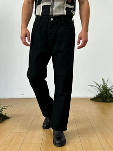 Front view of men's loose fit black washed denim jeans worn by a model in a minimalist studio