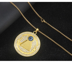 Macro shot of gold-plated pyramid evil eye pendant with crystal inlay and box chain