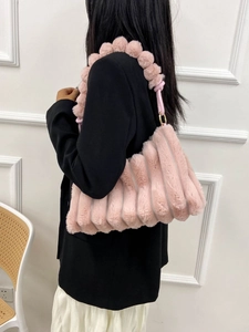 Pink plush handbag with striped texture and fuzzy ball strap for women over black blazer