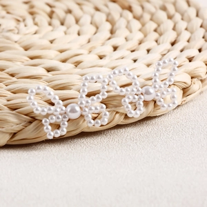Detail of handcrafted white pearl bow earrings featuring intricate beaded weaving and texture