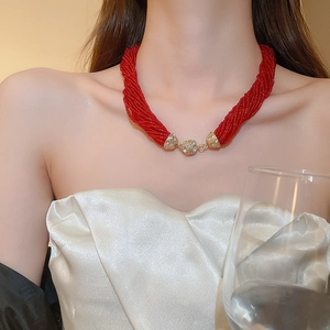 Detail of red multilayer seed bead necklace with gold rhinestone magnetic clasp on neck