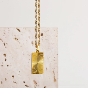 Detail of 18k gold butterfly heart pendant with radiant sunburst texture on gold chain