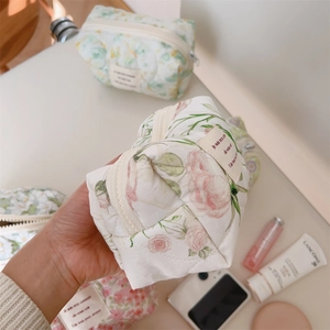 Close-up of quilted floral makeup bag with pink roses and yellow tulips in hand