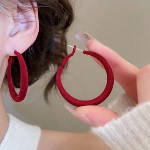 Gros plan sur une boucle d'oreille créole rouge avec texture velours et fini vibrant