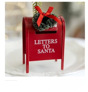 Mini red metal Santa mailbox with Christmas wreath and ribbon on a decorative white plate