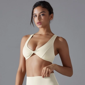 Detail of cream V-neck sports bra featuring central knot design and textured elastic fabric