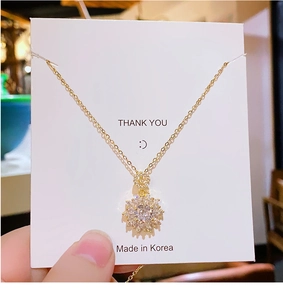 Close-up of golden sunflower pendant with sparkling white zircons on a delicate chain