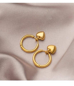 Detail of gold heart earrings on purple satin, showing polished finish and textures