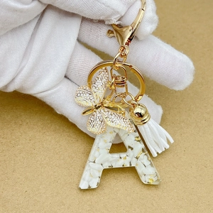 Macro detail of resin letter A keychain with gold foil flakes and white tassel accessory