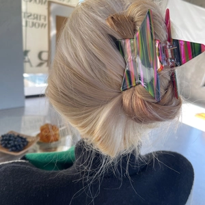 Star-shaped hair claw clip with colorful stripe pattern shown on a messy bun hairstyle