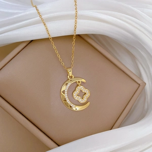 Close-up of gold clover moon necklace with sparkling crystals on a beige jewelry box