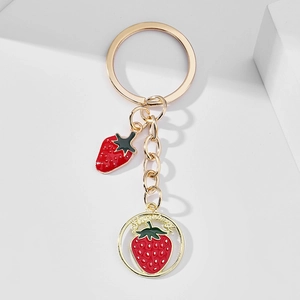 Close-up of golden strawberry charms on a metal keychain over white background