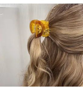 Detail of amber acetate hair claw clip with black patterns on light blonde wavy hair