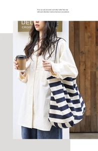 Detail of a large striped canvas tote bag in navy and white with slim handles