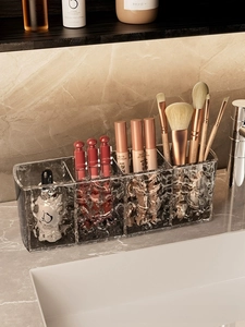Detail of clear acrylic makeup brush holder with water ripple texture on marble vanity