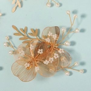 Detailed macro view of golden wire woven flowers with white pearls for bridal hair styling