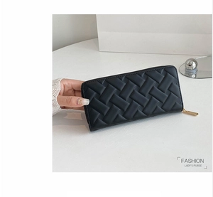 Close-up of black woven leather women's long wallet with a gold zipper on white desk