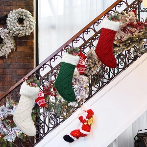 Three knitted Christmas stockings in red green and white hanging on a festive staircase
