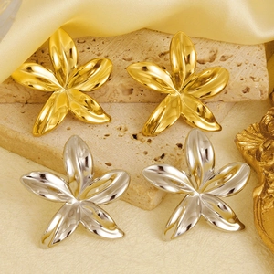 Vue détaillée de boucles d'oreilles fleurs dorées et argentées sur une pierre beige