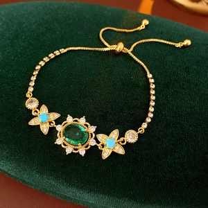 Détail d'un bracelet vintage en or avec pierre ovale verte sur fond de velours vert