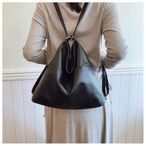 Detail of black lychee grain leather backpack showing soft texture and silver metal hardware