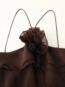 Dettaglio del fiore 3D e delle balze sovrapposte su un abito halter marrone