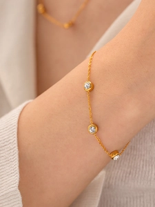 Gros plan d'un bracelet doré en acier inoxydable avec trois cristaux sertis clos