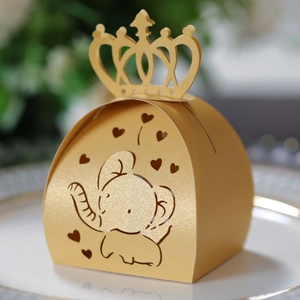 Detail showing the intricate hollow crown and baby elephant design on a gold candy box