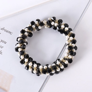 Close-up of woven hair tie featuring black faceted beads and white pearls with gold wire