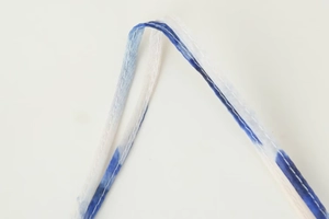 Gros plan sur les coutures à double aiguille du tissu tie-dye bleu de la robe en V