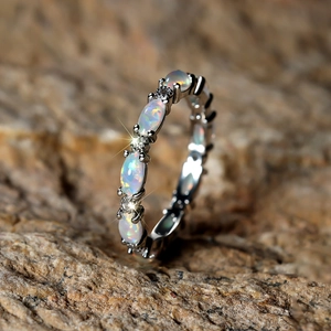 Macro view of silver opal ring featuring oval white opals and tiny round accent diamonds