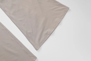 Close-up of double-stitched hem on khaki high-waist flared trousers in woven fabric