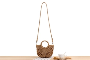 Detailed weave of a semi-circular paper rope beach bag with circular handles on a wooden table