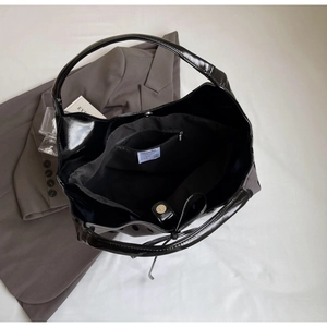 Detailed interior of glossy black tote bag with magnetic clasp and zipper pocket