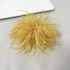 Detailed view of a bright yellow ostrich feather brooch on a grey textured background