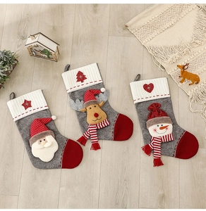 Trois chaussettes de Noël en tricot avec Père Noël, renne et bonhomme de neige au sol